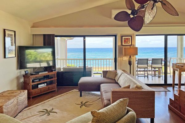 open concept living area with large ceiling fan enjoys expansive ocean views through two sets of sliding glass doors