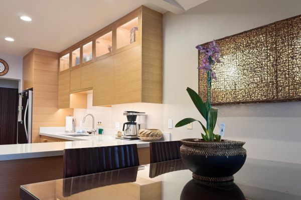 open dining area has tall glass-topped dining table and unique wall lighting for warm ambiance