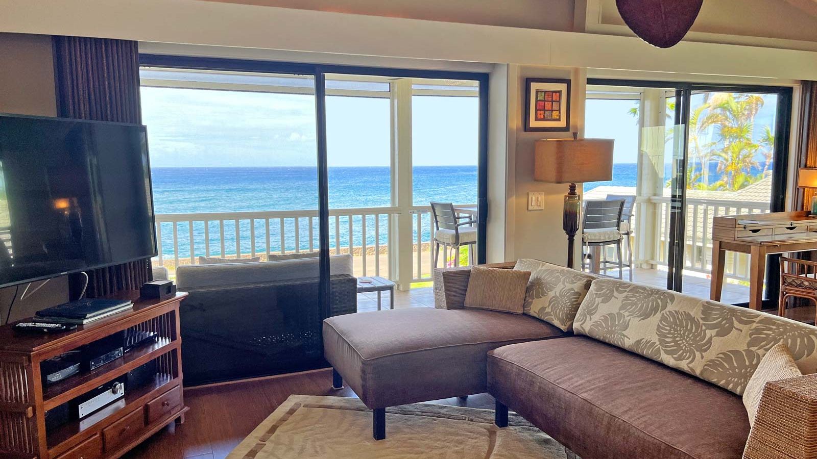 ocean view open living area with big screen TV, stereo, sectional couch, and comfortable chairs